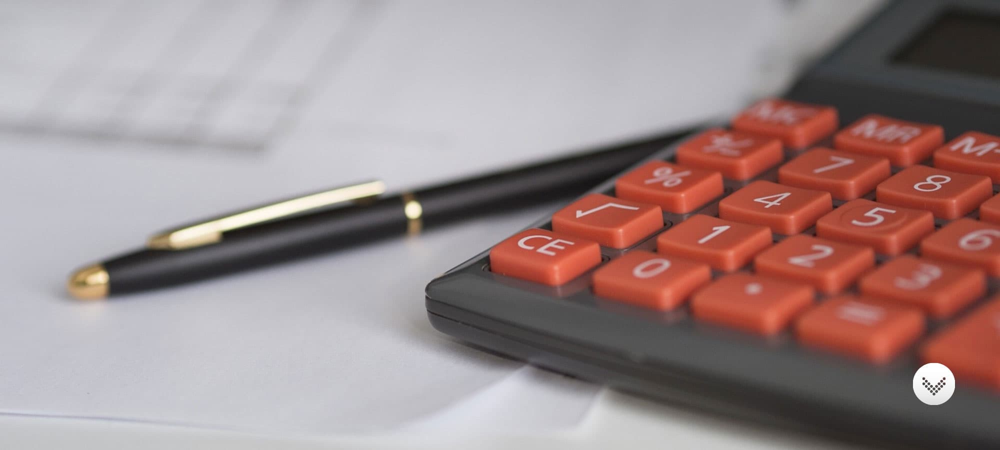 A calculator and pen situated on top of a paper form quote.