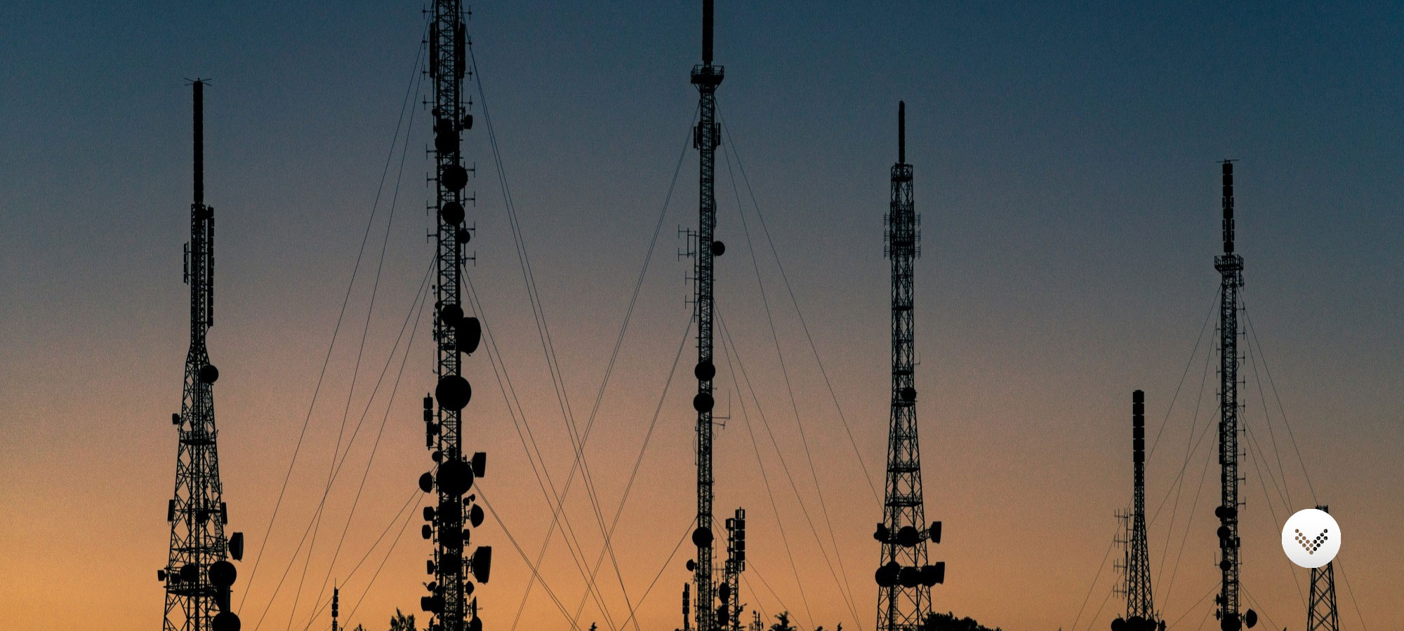 Several cell phone towers lined up and captured at sunset.